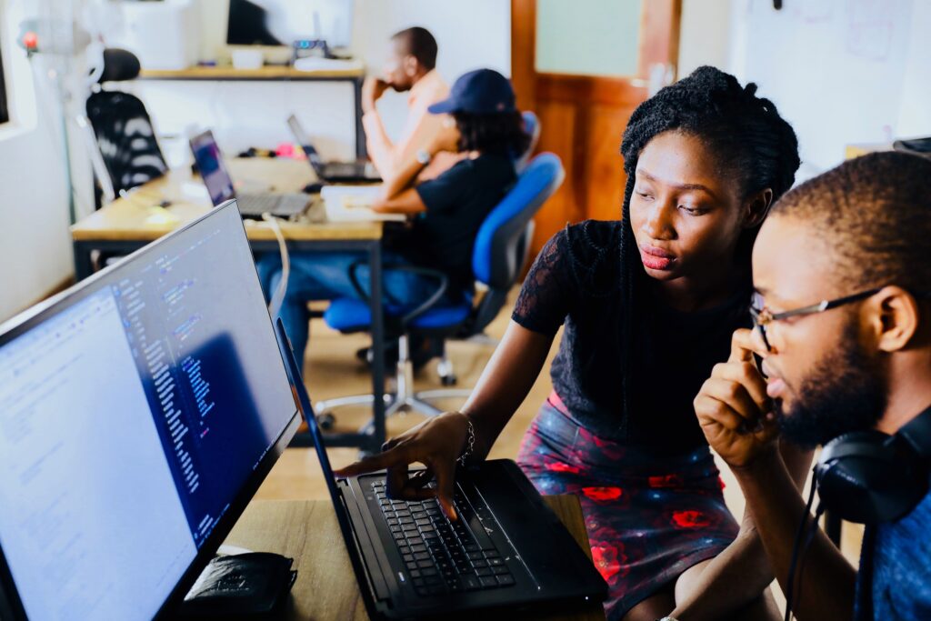 imagem mostra uma mulher e um homem, ambos negros, trabalhando em frente a um computador.